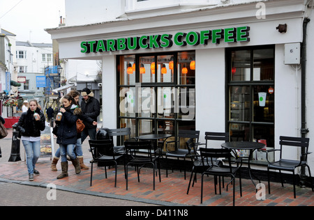 I giovani con caffè da asporto da Starbucks coffee shop in Brighton è Il distretto di corsie Foto Stock