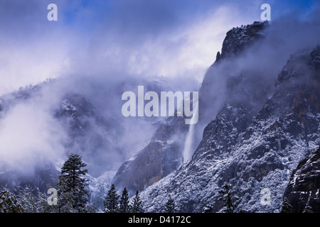 Bellissima scenic primavera nevicata nel Parco Nazionale di Yosemite creando splendide nebbia atmosferica nuvole basse nelle montagne intorno al Parco Nazionale di Yosemite Falls Foto Stock