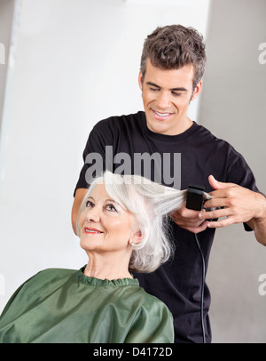 Parrucchiere Senior di raddrizzatura donna capelli Foto Stock