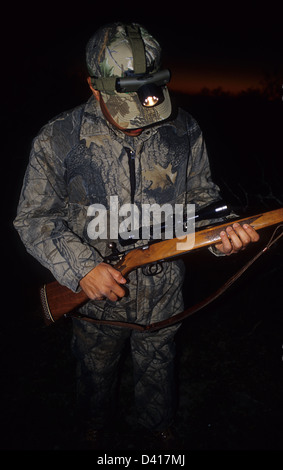 South Texas cacciatore dei cervi esaminando il suo fucile da caccia con un proiettore Foto Stock