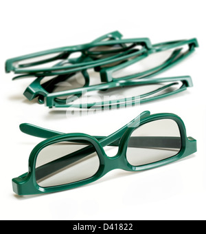 Coppia di verde 3d occhiali polarizzati per la visione di 3-d film per il cinema isolata contro bianco con pila di specifiche utilizzate in background Foto Stock