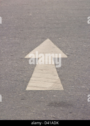 Bianco freccia direzionale su asfalto Foto Stock
