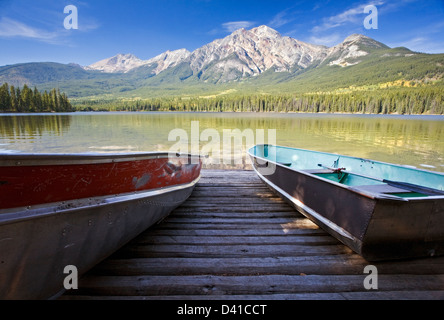 Barche a remi sul dock con la montagna a piramide. Foto Stock