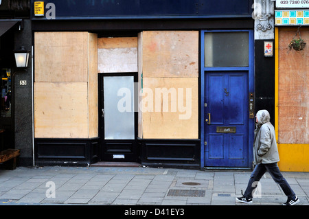 Un uomo cammina passato un intavolato shop nel centro di Londra, Regno Unito. Foto Stock