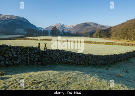 Stile asciutto su muro di pietra frosty mattina guardando verso il Borrowdale Fells, Cumbria, Parco Nazionale del Distretto dei Laghi, England, Regno Unito Foto Stock