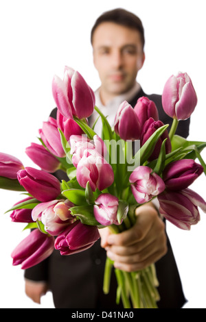 Un uomo tiene fuori un mazzo di tulipani, profondità di campo ridotta con focus sulla parte anteriore i tulipani. Foto Stock