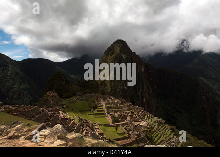 Machu Picchu rovine Inca di Huayna Picchu mountain in background scendendo nuvole sopra la valle sacra Foto Stock