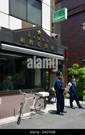 Due poliziotti in piedi al di fuori di un quartiere koban o casella di polizia, nel centro cittadino di Ueno, Tokyo, Giappone. Foto Stock