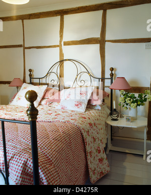 Controllare rosa e rose-quilt modellato sul ferro battuto letto nel paese di travi di camera da letto Foto Stock