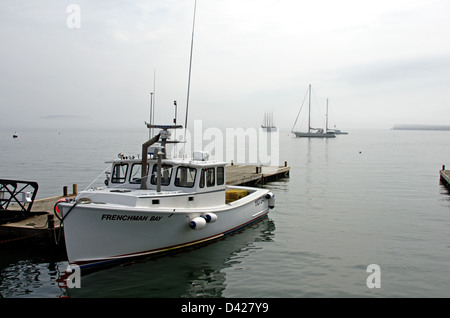 Un raggio di sole si rompe in un banco di nebbia alla luce di una aragosta barca legato fino al molo della città, Bar Harbor, Maine. Foto Stock