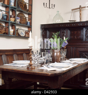 In pannelli di quercia in parete tradizionale sala da pranzo con rovere sedimentare e bicchieri e le regolazioni del posto sul tavolo con vaso di giacinti blu Foto Stock