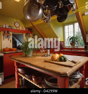 Padelle appeso sul rack sopra isola in legno unità in rosso e verde cucina attico Foto Stock