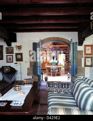 Verde + bianco divano a strisce di legno e un tavolo da caffè in spagnolo soggiorno con legno rustico travi a soffitto e Foto Stock