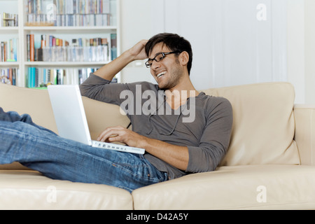 Un uomo molto comodo di navigare su internet usando un computer portatile. Foto Stock