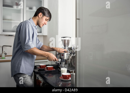 Un ragazzo occupato il caffè in cucina. porta frigo sulla destra è fornito come copia di spazio. Foto Stock