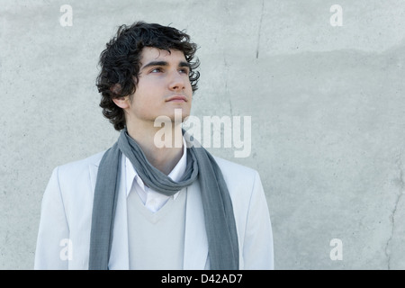 Un giovane uomo che guarda verso l'alto, che indossa un elegante vestito di luce per la primavera e l'estate, in sottili sfumature e colori. Foto Stock