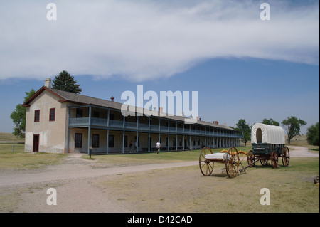 Blue sky view white baldacchino Prairie Schooner carro anteriore permanente caserma di cavalleria edificio, Fort Laramie, Wyoming USA Foto Stock