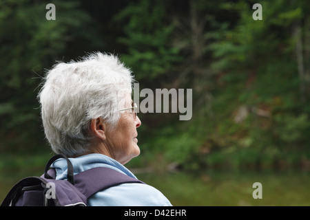 Malinconici senior donna seduta walker in pioggia in tranquilli dintorni del lago Taubensee, Ruhpolding, Chiemgau, Baviera, Germania Foto Stock