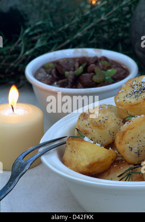 Close-up di ciotola di patate arrosto accanto a candela accesa Foto Stock