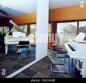 Parete specchiata dietro il pianoforte a coda e chrome+pelle sedia a sbalzo in ardesia moderno-pavimentato country living room Foto Stock