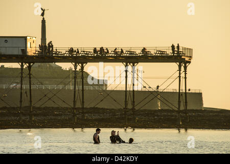 Il 2 marzo 2013. Aberystwyth, Wales, Regno Unito. In una calda serata primaverile, persone nuotare in mare di fronte o Aberystwyth di epoca vittoriana pier Foto Stock