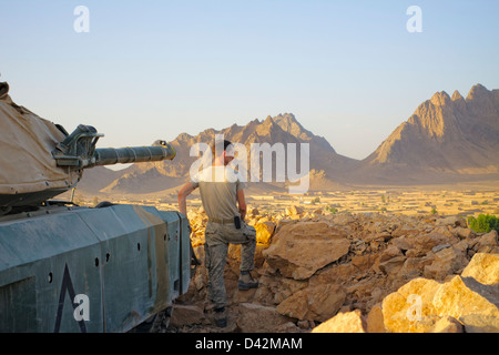 In cima a una posizione difensiva, un soldato che si affaccia su un villaggio nella provincia di Kandahar, Afghanistan. Foto Stock