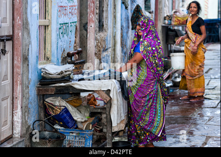 Le donne abiti di ferro al fresco come parte di un piccolo commercio basato domestico in Ajmer, Rajasthan, India. Essi indossano sari colorati Foto Stock