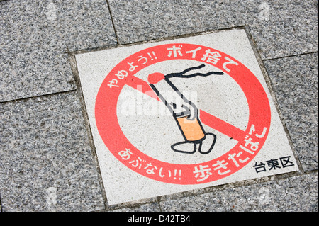 Il cartello marciapiede ricorda ai pedoni di Taito-ku, Tokyo, di non camminare e fumare sulle strade pubbliche perché è pericoloso., Giappone. Foto Stock