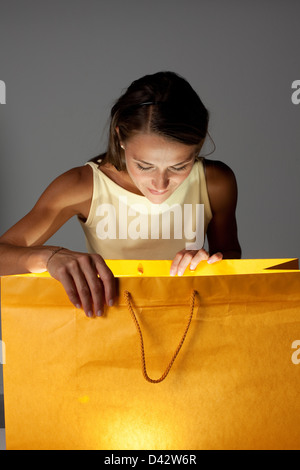 Freiburg, Germania, una giovane donna guarda curiosamente in una borsa per la spesa Foto Stock