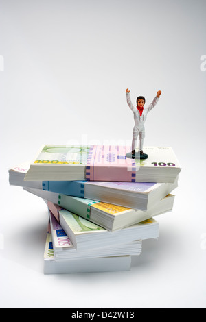 Freiburg, Germania, figura con i bracci sollevati in piedi su una pila di banconote in euro Foto Stock