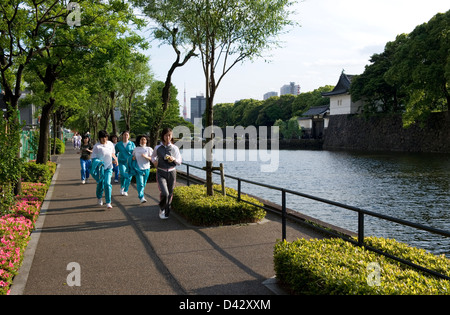 Per gli amanti del jogging femmina facendo giri intorno a 5 chilometro fossato esterno che circonda Corso Palazzo Imperiale, sito del vecchio castello di Edo in Tokyo. Foto Stock