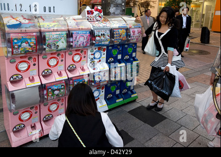 Ragazze acquisto da un 'gachapon,' o toy-in-un-capsule distributore, popolare con i bambini e gli adolescenti in Giappone. Foto Stock