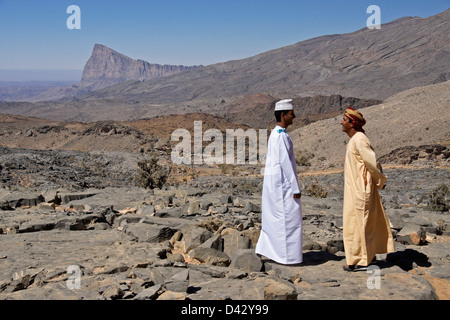 Omani gli uomini che parlano in paesaggio roccioso vicino a Nizwa, Oman Foto Stock