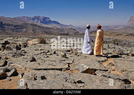 Omani gli uomini che parlano in paesaggio roccioso vicino a Nizwa, Oman Foto Stock