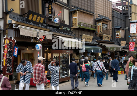 I turisti e gli amanti dello shopping passeggiando passato ricreato old-style di negozi nel quartiere dei negozi e dei divertimenti di Asakusa, Tokyo. Foto Stock