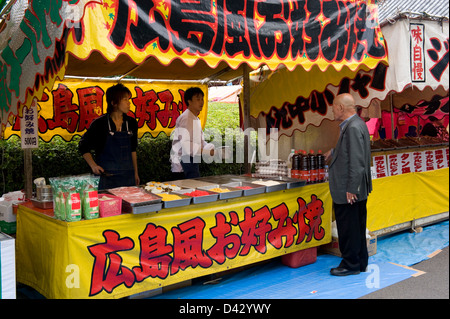 Roten stand di vendita è famoso okonomiyaki di Hiroshima, una pizza giapponese con cavolo, carne e uova, ad un Festival in Tokyo. Foto Stock