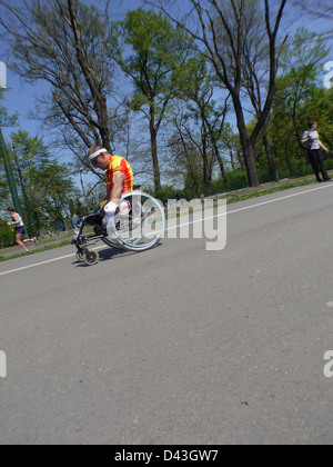 Maratona di portatori di handicap racer prendendo parte a Cracovia Internazionale Marathon su una sedia a rotelle Foto Stock