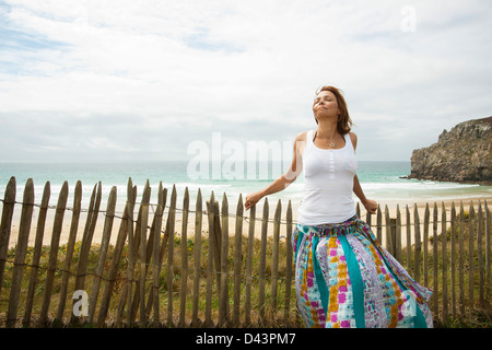 Donna appoggiata sul Sandfence presso la spiaggia, Camaret-sur-Mer, Crozon Penisola, Finisterre, Bretagna Francia Foto Stock