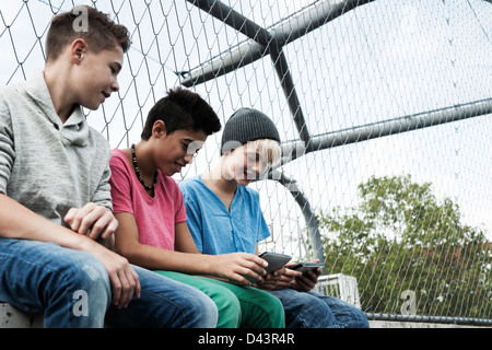 Tre ragazzi giocare i video giochi nel parco giochi, Mannheim, Baden-Württemberg, Germania Foto Stock