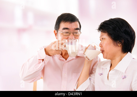Sud-est asiatico coppia matura di bere latte di soia in casa. Foto Stock