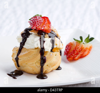 Choux crema snack topping di glassa e fragola sul piatto Foto Stock