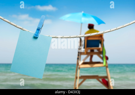 Nota paper agganciata su una fune. Sfondo di spiaggia Foto Stock