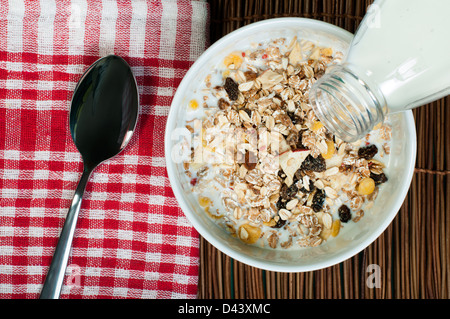 Muesli Prima colazione in package.bottiglia di latte e cucchiaio. Versare il latte in una ciotola Foto Stock