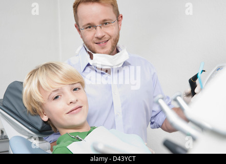 Ritratto di ragazzo in poltrona del dentista con il dentista per appuntamento, Germania Foto Stock