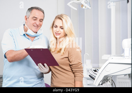 Dentista spiegando grafico medico al paziente in studio dentistico, Germania Foto Stock