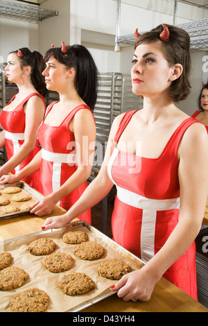 Donne che indossano diavolo corna a lavorare in una panetteria di Oakland, contea di Alameda, California, Stati Uniti d'America Foto Stock