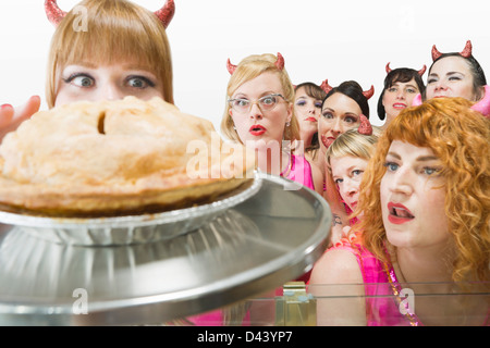 Donne che indossano diavolo corna guardando la torta di mele Foto Stock