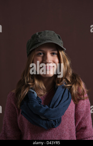 Ritratto di ragazza sorridente alla fotocamera, con berretto da baseball e sciarpa, Studio shot su sfondo nero Foto Stock