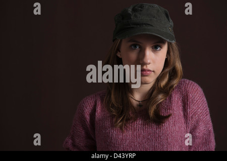 Close-up verticale del Biondo, ragazza adolescente con berretto da baseball, Studio shot su sfondo nero Foto Stock