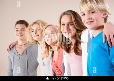 Ritratto di un gruppo di ragazzi adolescenti e le ragazze in piedi in una fila con le braccia intorno alle spalle, Studio shot su sfondo bianco Foto Stock